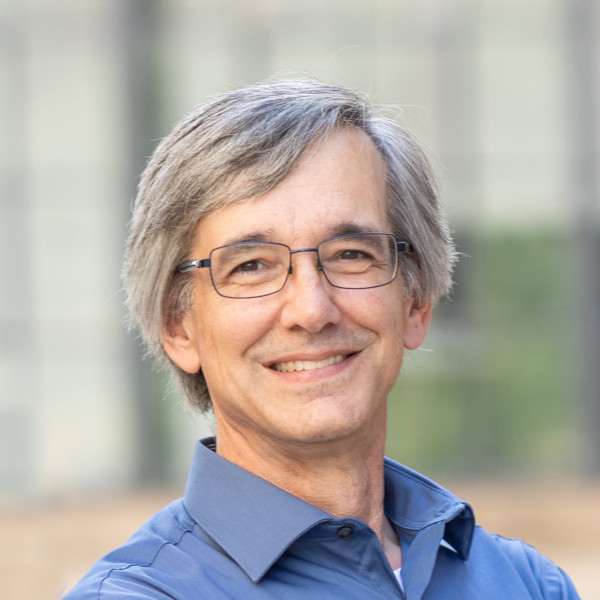 Headshot photograph of Mathematics and Statistics department head Stephen Tate, he has grey hair, wears glasses, a blue shirt, and is smiling
